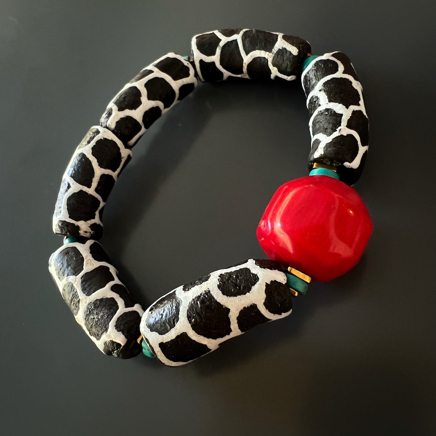 Vibrant red coral bead, the centerpiece of the African Zebra Red Bracelet, symbolizing energy and protection.