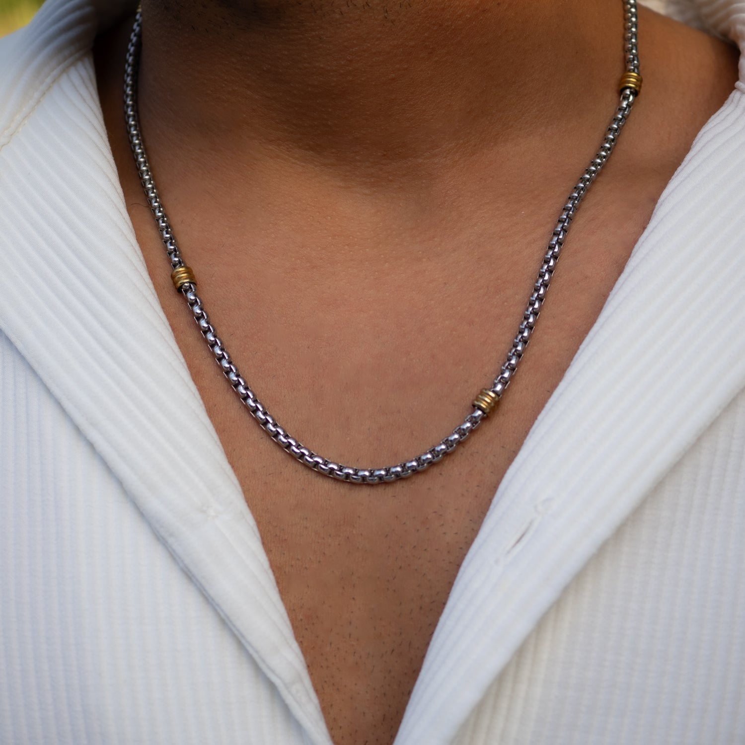 Close-up of two-tone chain necklace in stainless steel, featuring sleek silver and gold design.