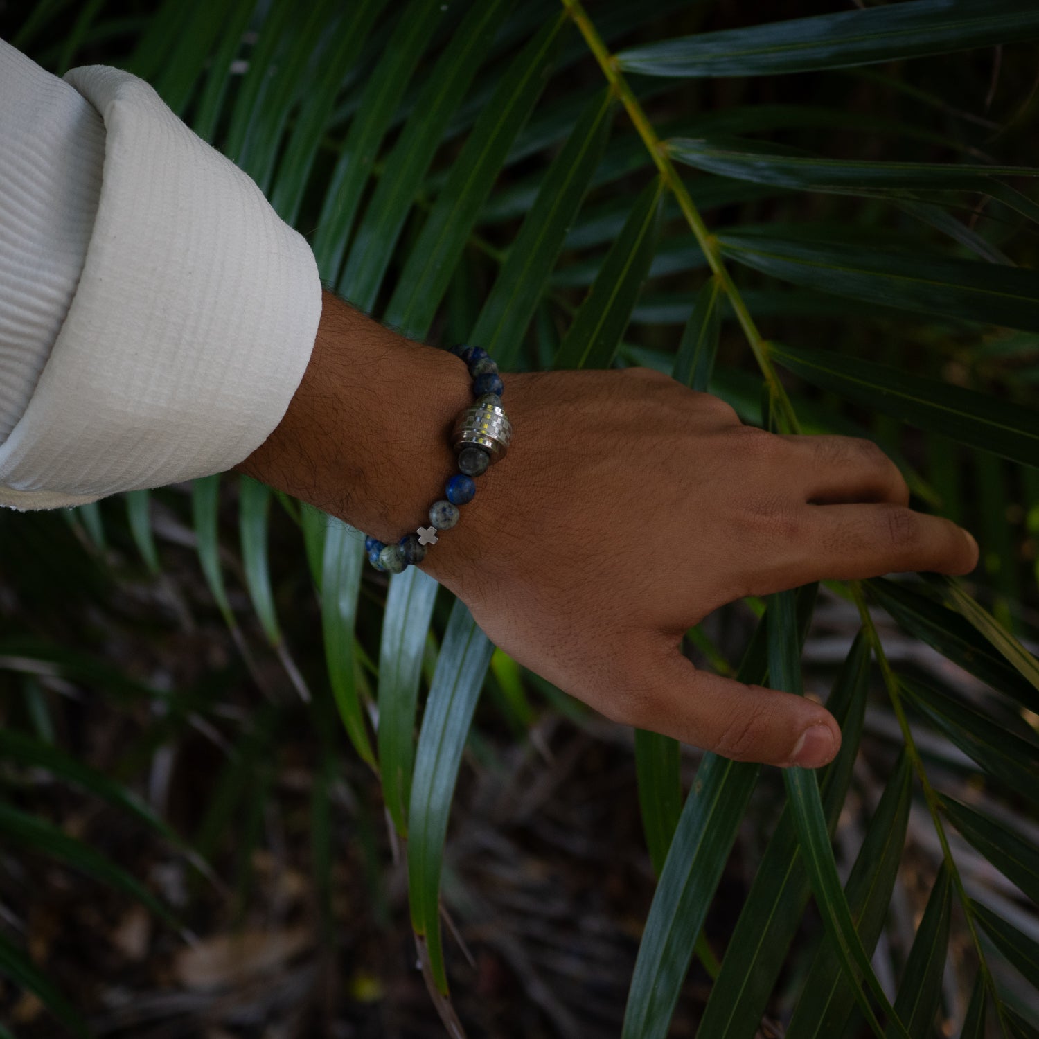 Handmade bracelet featuring 8mm azurite stones, steel Amor centerpiece, and sterling silver logo.