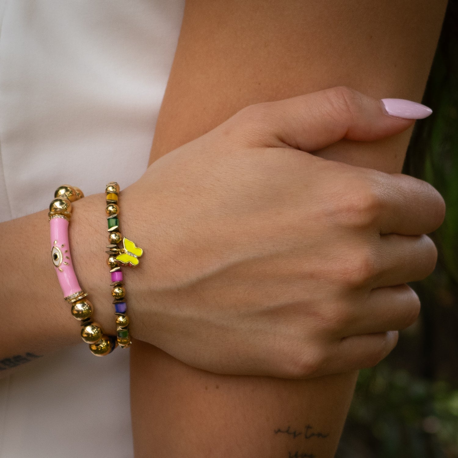 Handmade bracelet duo featuring pink enamel evil eye tube bead and yellow butterfly charm