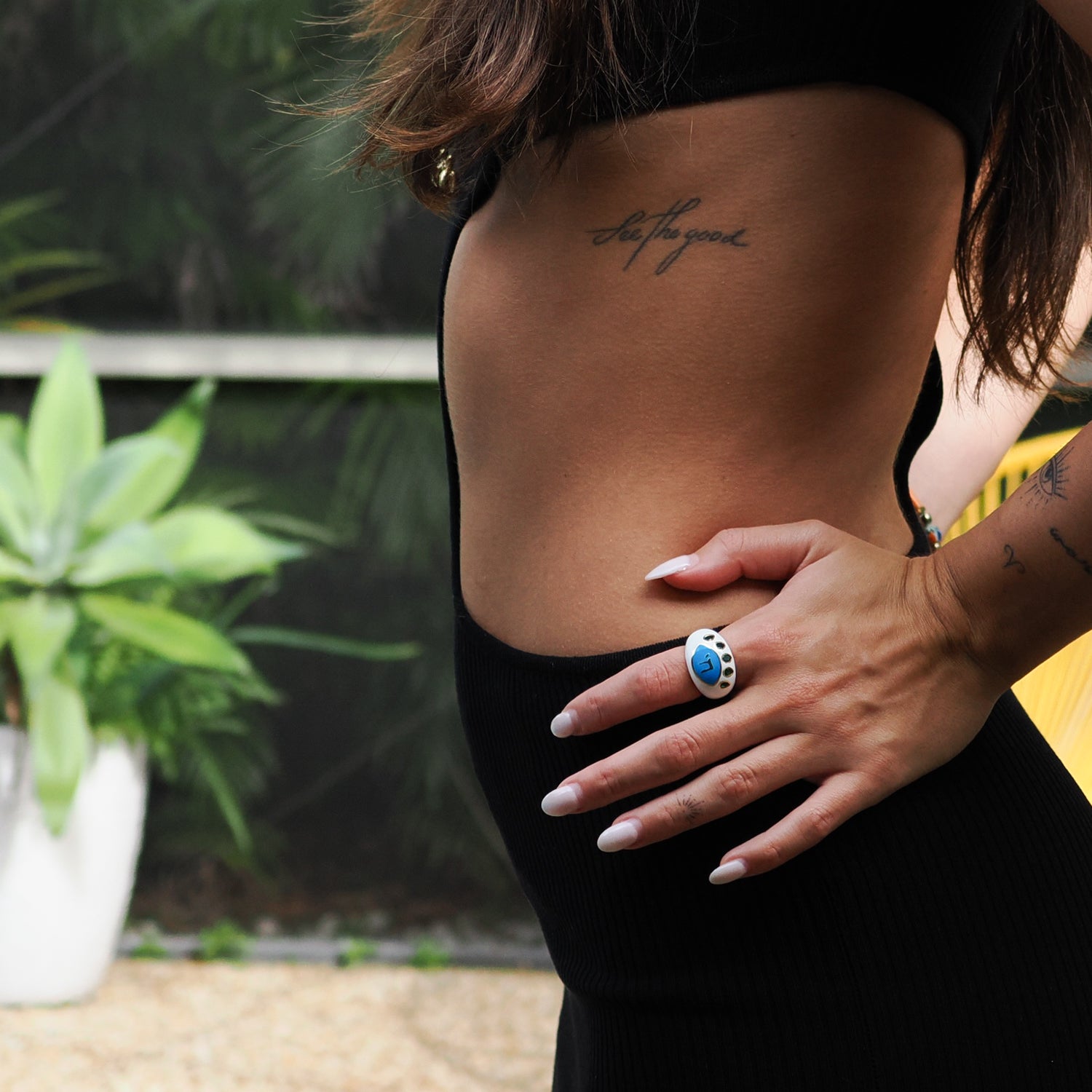 Elegant white enamel ring featuring a protective eye design with a Chai symbol and green emerald details.