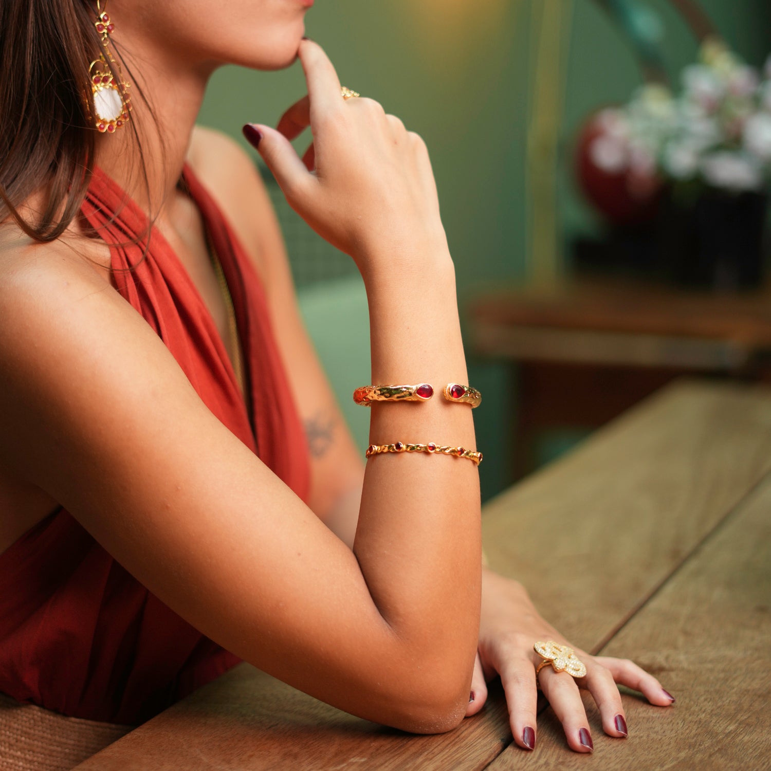 Bold gold cuff bracelet with vibrant teardrop ruby stones, exuding sophistication and elegance, inspired by Cleopatra's legendary allure.