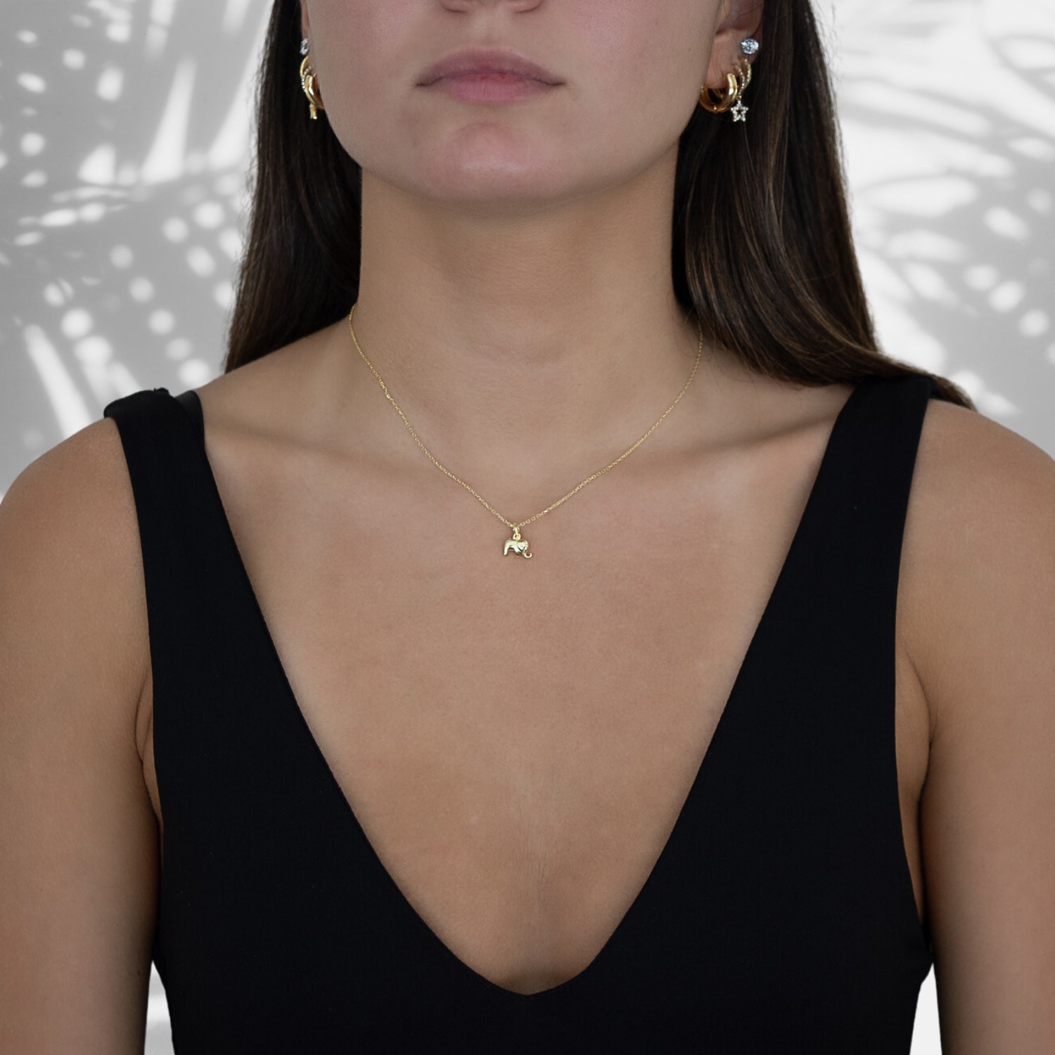 The Dainty Gold Elephant Necklace adding a touch of charm and sophistication to the model's outfit, capturing attention with its symbolic elephant pendant.