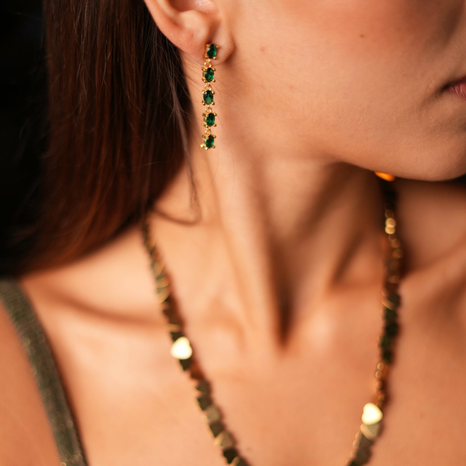 Refined earrings with a gold-plated frame and cascading emerald stones, creating a sleek and sophisticated design.