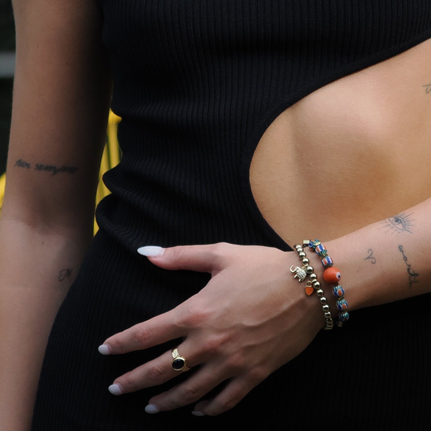 African beaded bracelet set adorned with an orange enamel heart and a gold elephant charm, symbolizing wisdom.