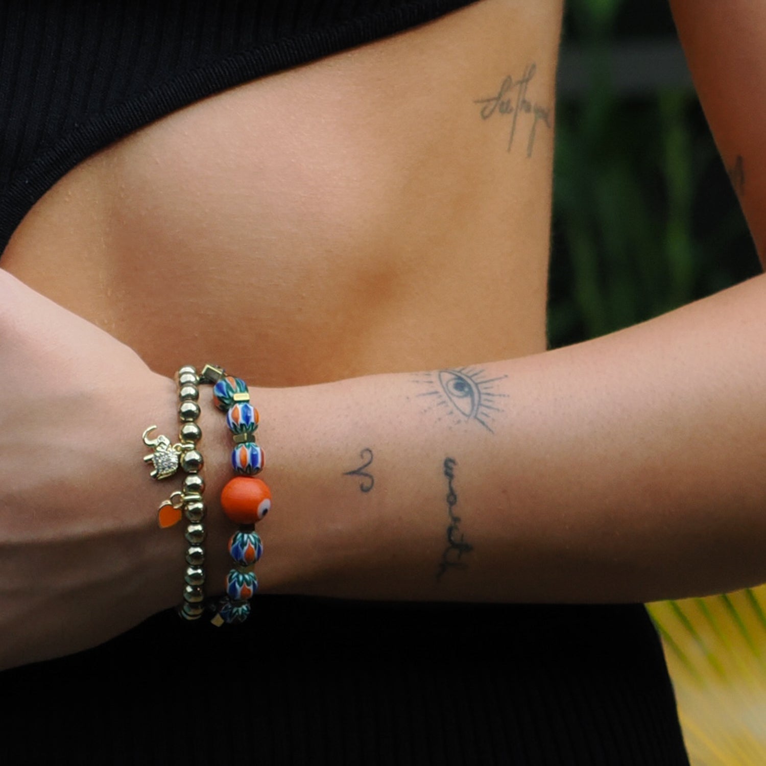 Handcrafted bracelet set featuring an orange enamel heart charm, gold elephant charm, and African beads.