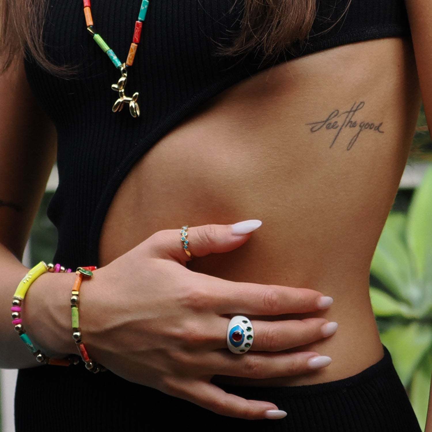 Elegant Evil Eye ring with a wide white enamel band, ruby and emerald details, and 18K gold plating.