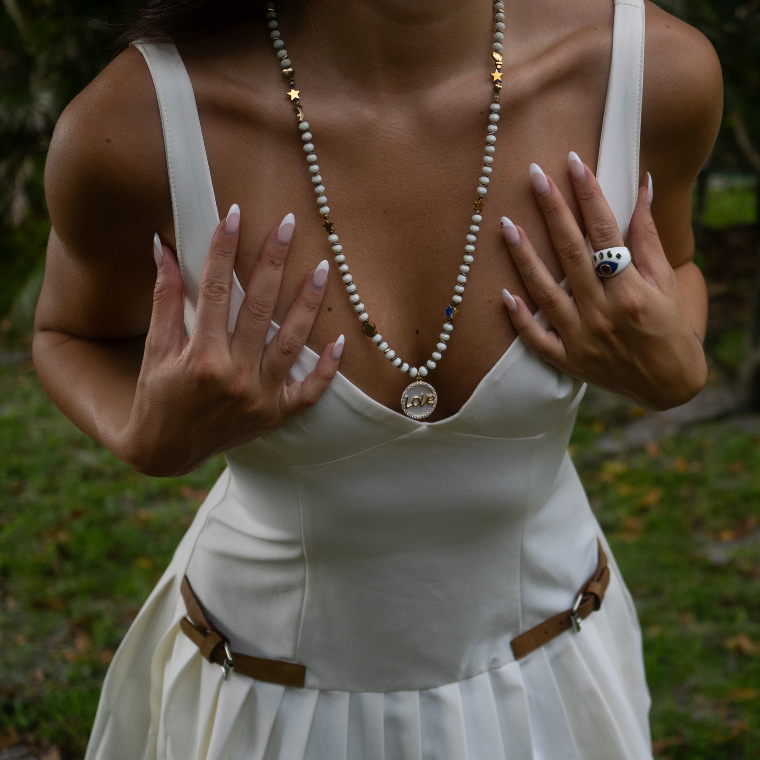 Handmade crystal and charm necklace with gold “Love” pendant and celestial accents.