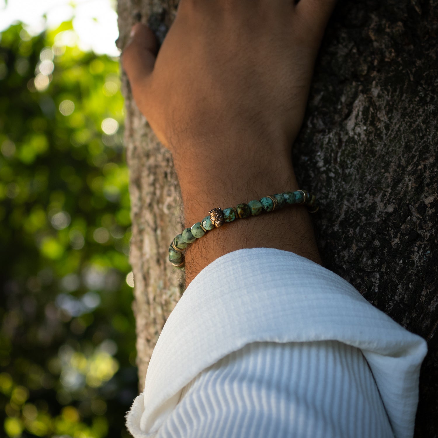 Turquoise beaded bracelet with bronze king skull charm, symbolizing good fortune and courage.