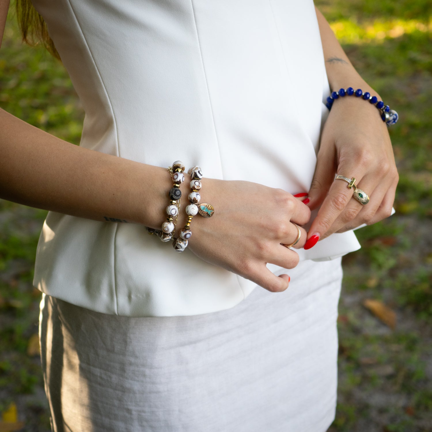 Close-up of handmade blue enamel fish charm and gold-plated elephant charm on bracelet.