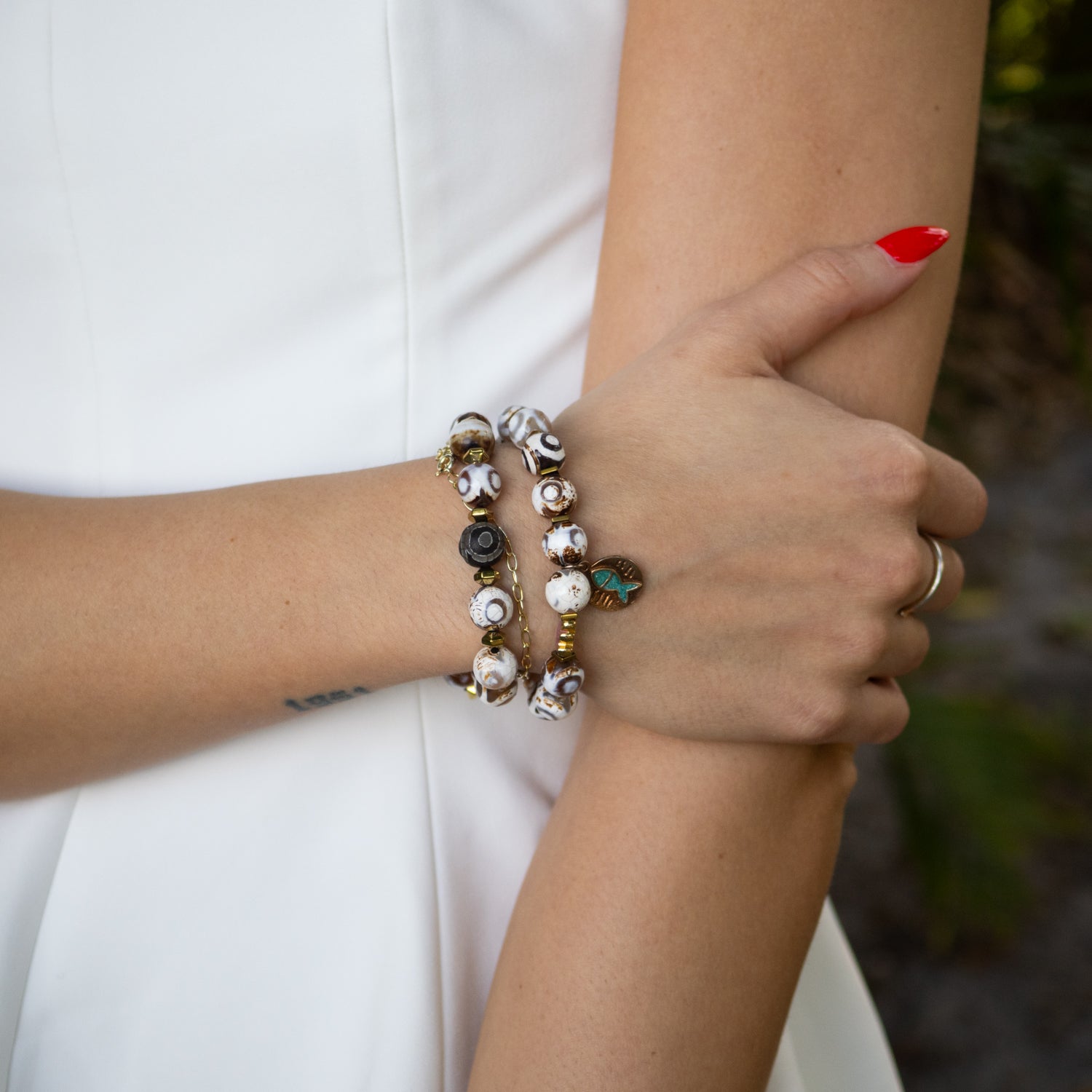 Handmade Lucky Fish bracelet stack with Tibetan mantra bead and blue glass beads.