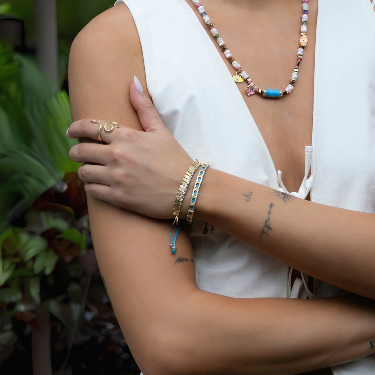 Close-up of gold fish charm bracelet on vibrant turquoise cord, handmade for positivity.