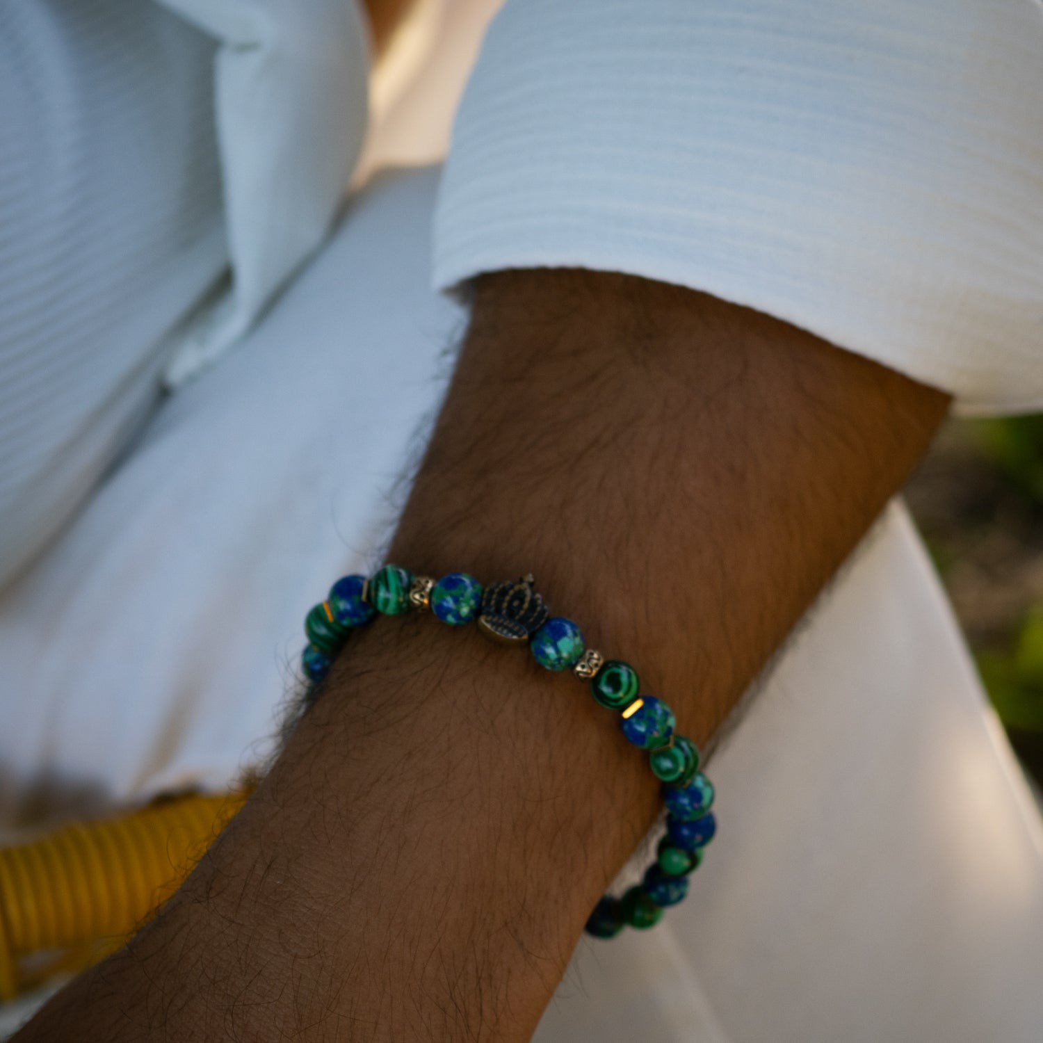 Malachite beaded bracelet with gold hematite spacers and bronze gold-plated crown charm.