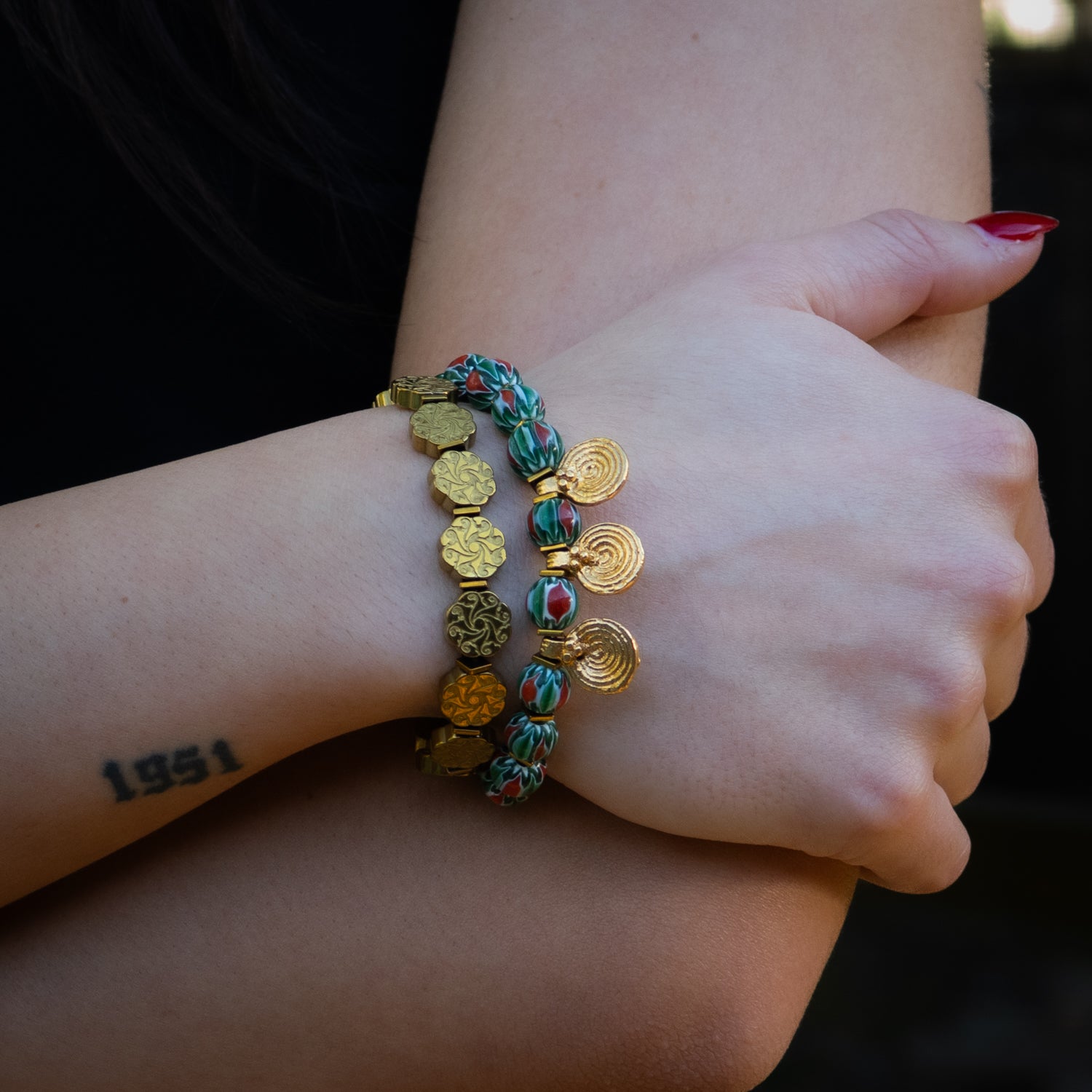 Colorful African bead bracelet with bold red and green tones and triple spiral gold accents