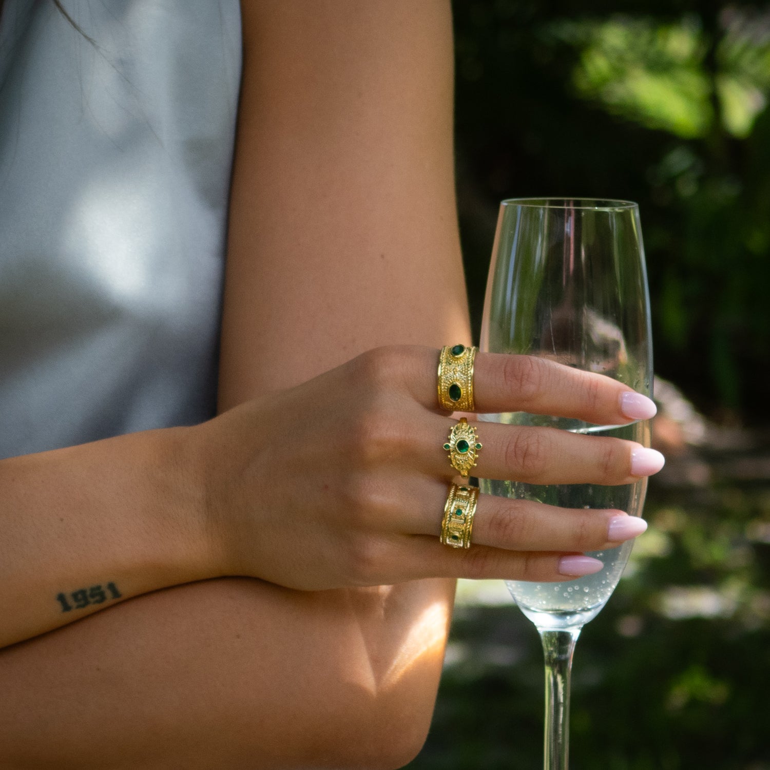 Handcrafted bronze ring plated in 24K gold featuring five evenly spaced emerald gemstones.