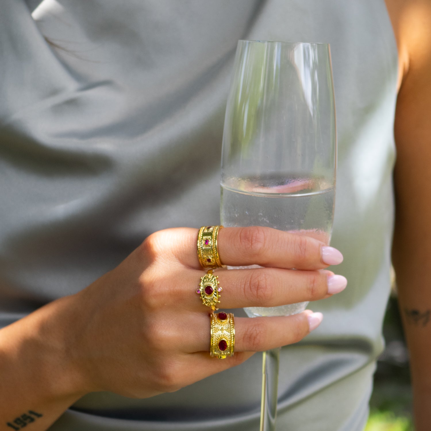 Handcrafted bronze ring plated in 24K gold featuring five radiant ruby gemstones.