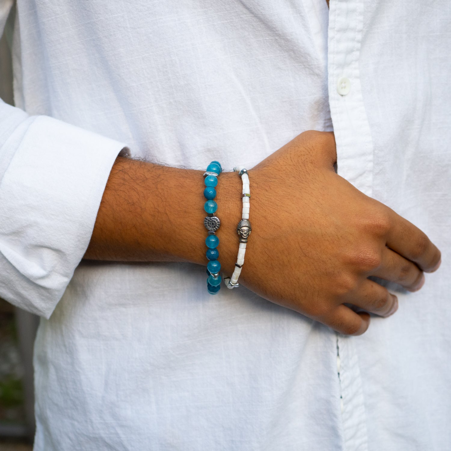 Silver seashell charm bracelet with blue jade stones for clarity, shown with matching pearl bracelet.