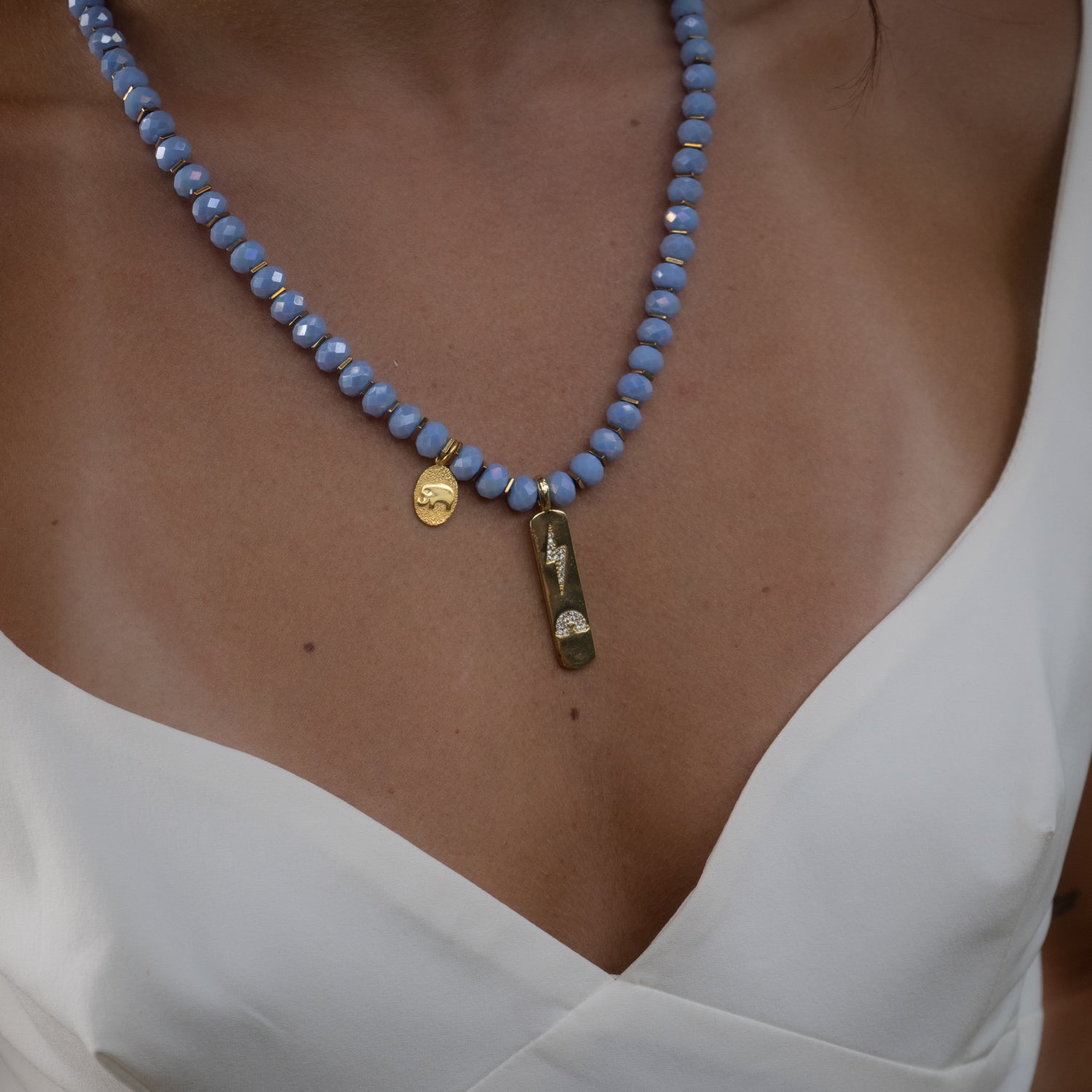Empowering necklace with gold lightning pendant and delicate elephant charm.