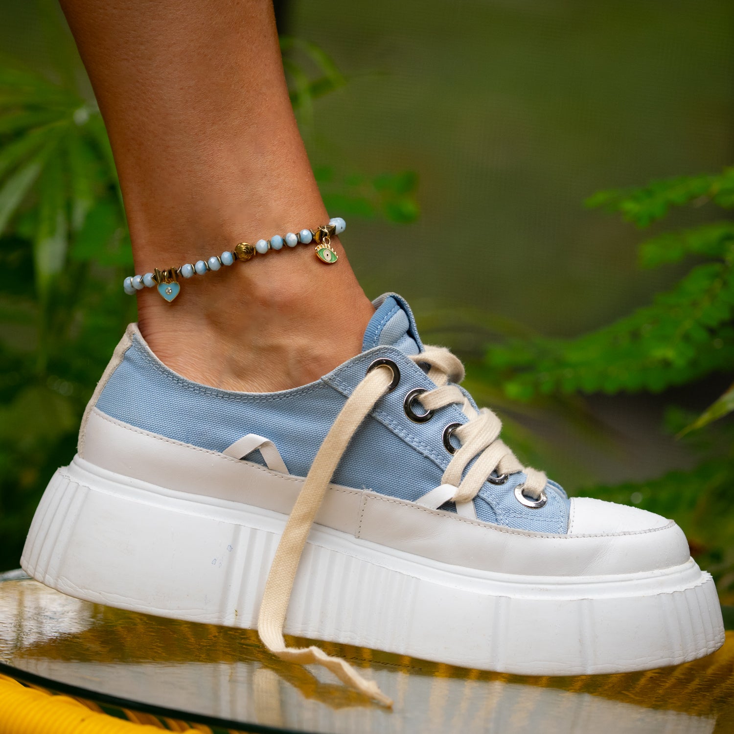 Sparkling blue crystal anklet with protective charms and gold accents.