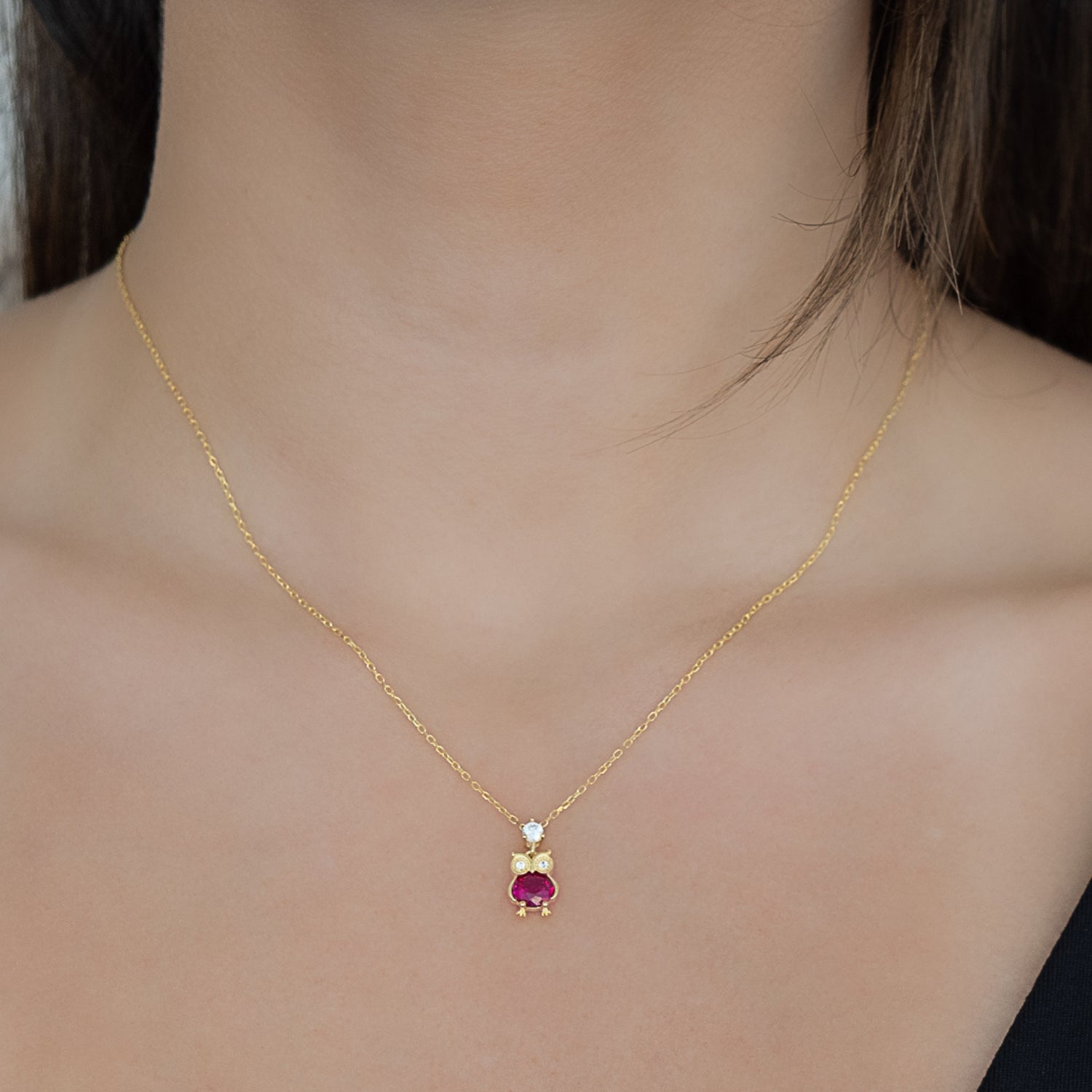 A model wearing the Ruby Owl Necklace, showcasing its elegance and sophistication as it gracefully adorns their neckline.
