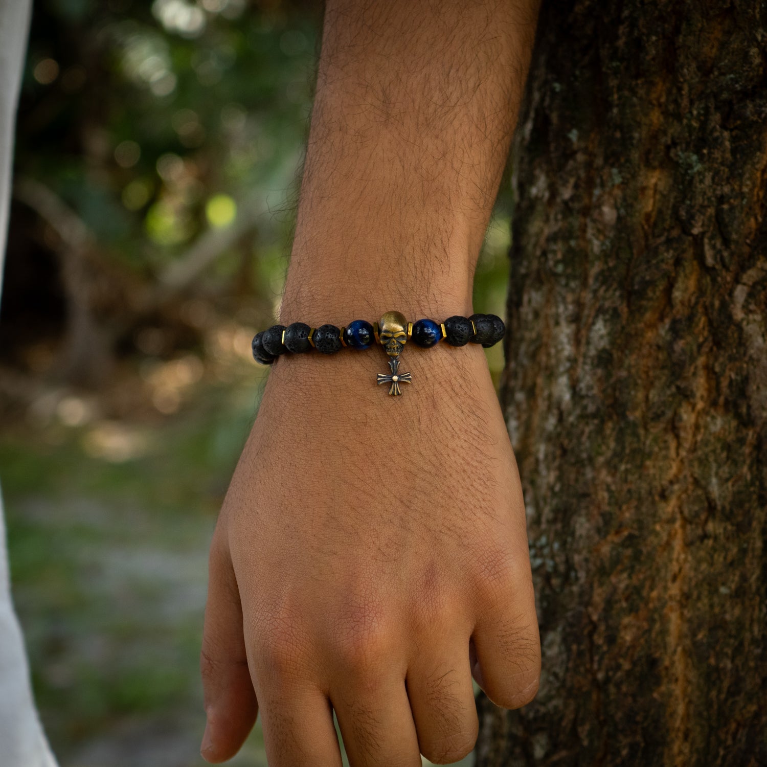 Black lava rock bracelet with bronze skull charm and fleur de lis bead, accented by blue tiger eye.