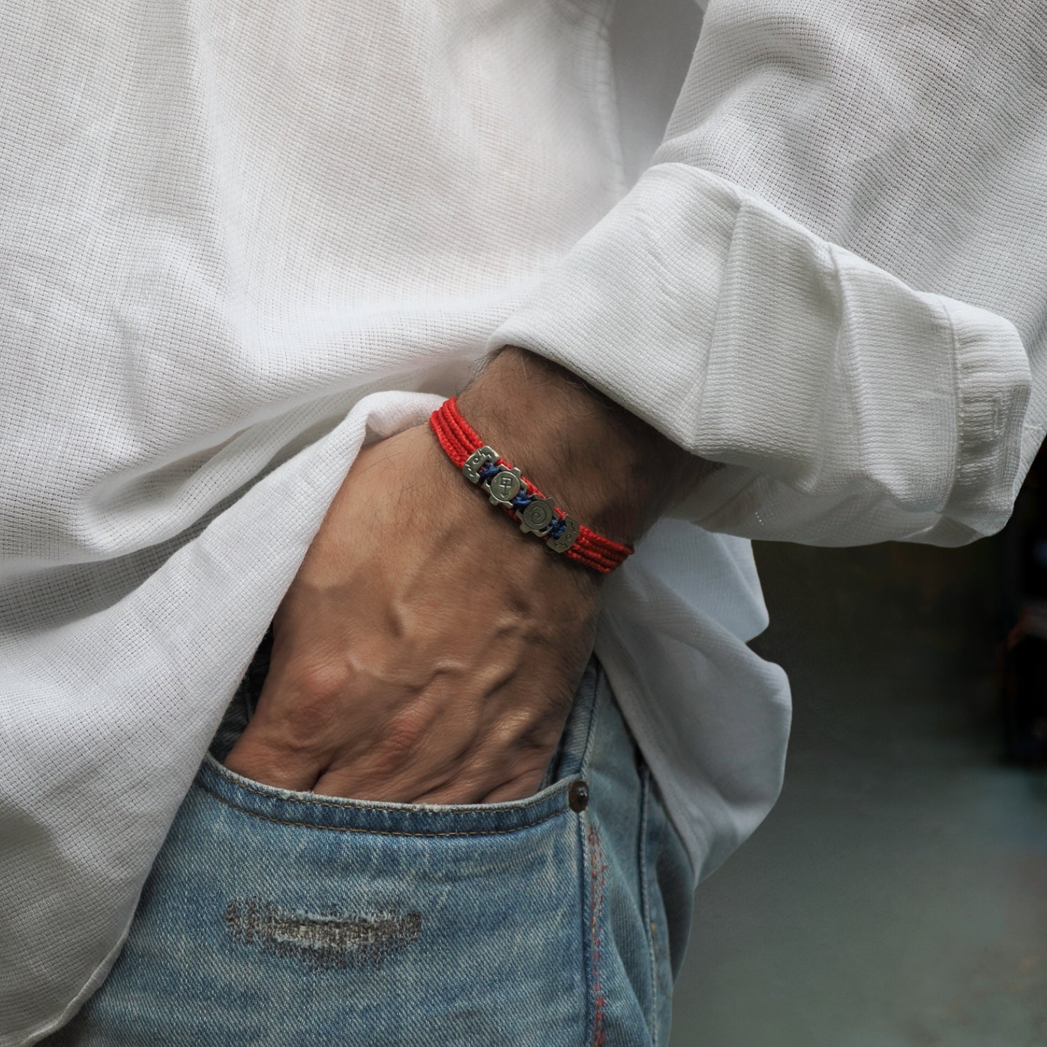 Handcrafted red cord bracelet with sterling silver spiritual symbols representing emotion and the soul.