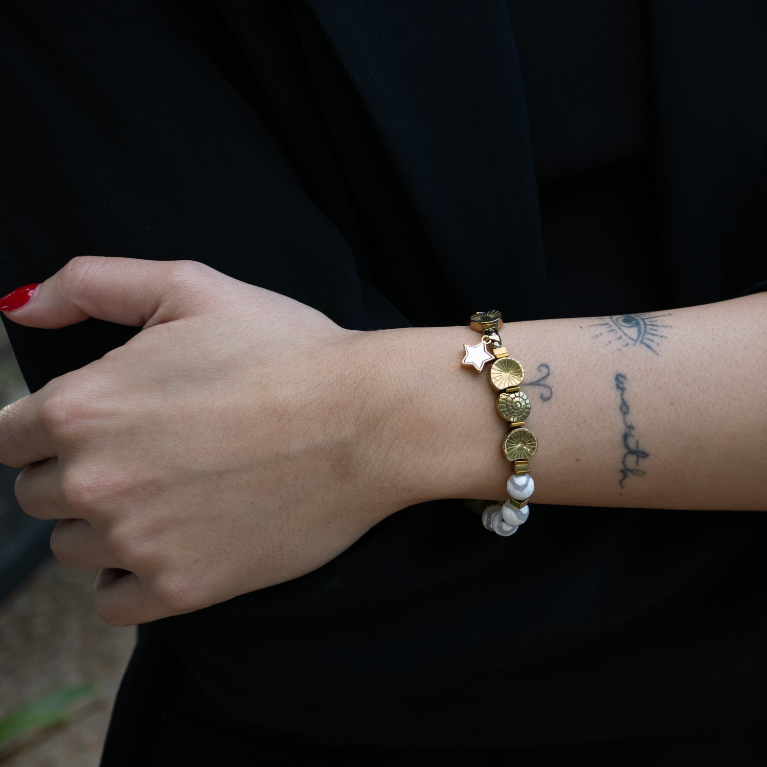 Wrist view of handmade jade and agate bracelet with gold spiral and star details