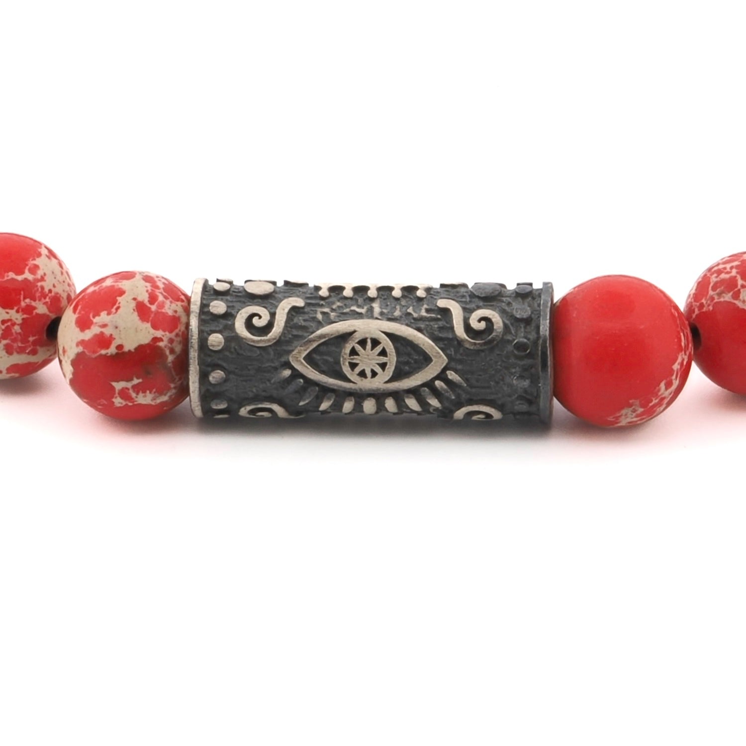 Close-up of a red jasper beaded bracelet with a sterling silver Evil Eye charm symbolizing protection and courage.