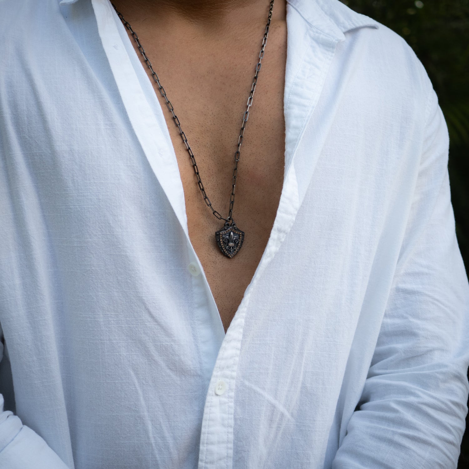 Sterling silver shield necklace with hand-engraved fleur de lis pendant and brown zircon stones.