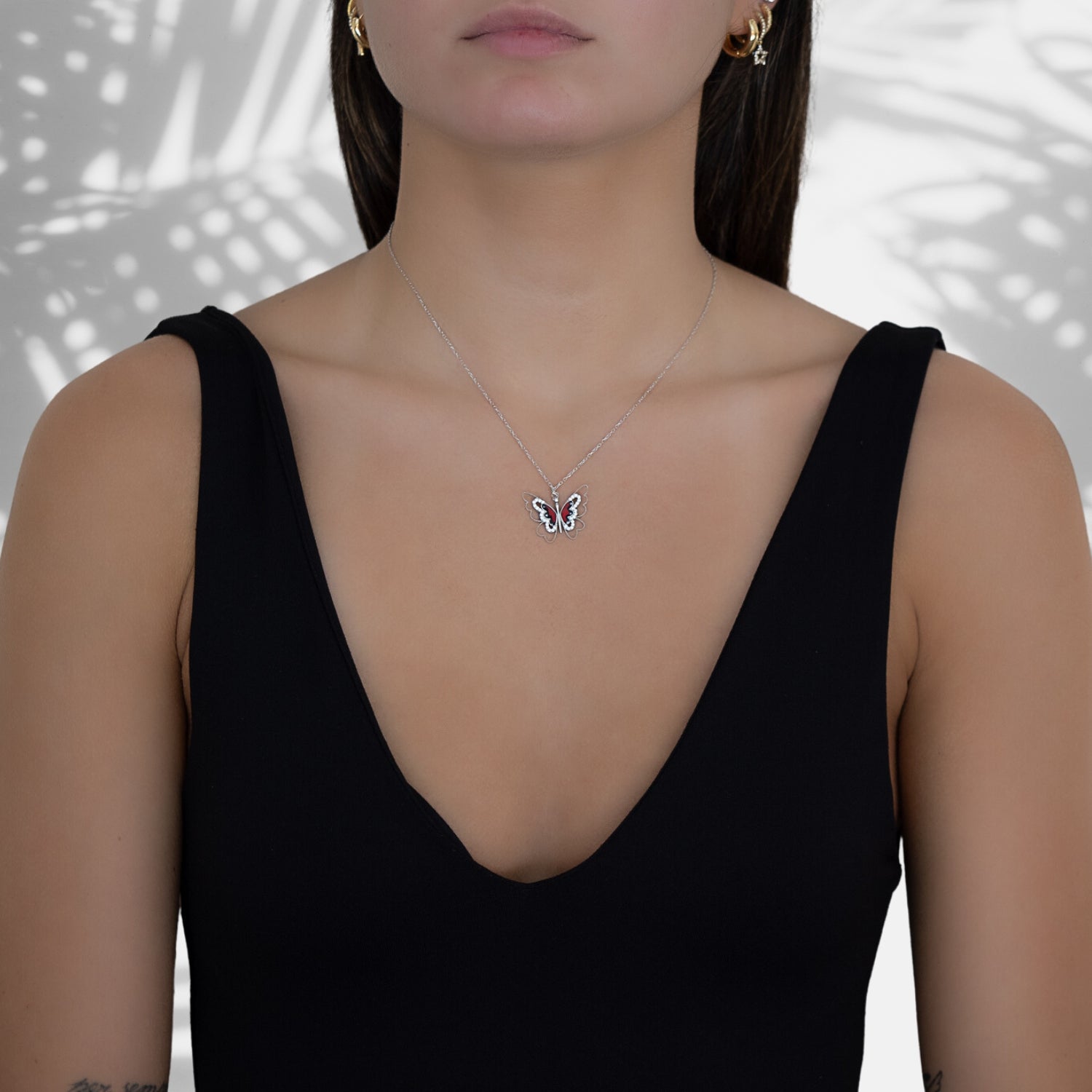 The Sterling Silver Peace Red Butterfly Necklace complementing the model&#39;s attire with grace and style.
