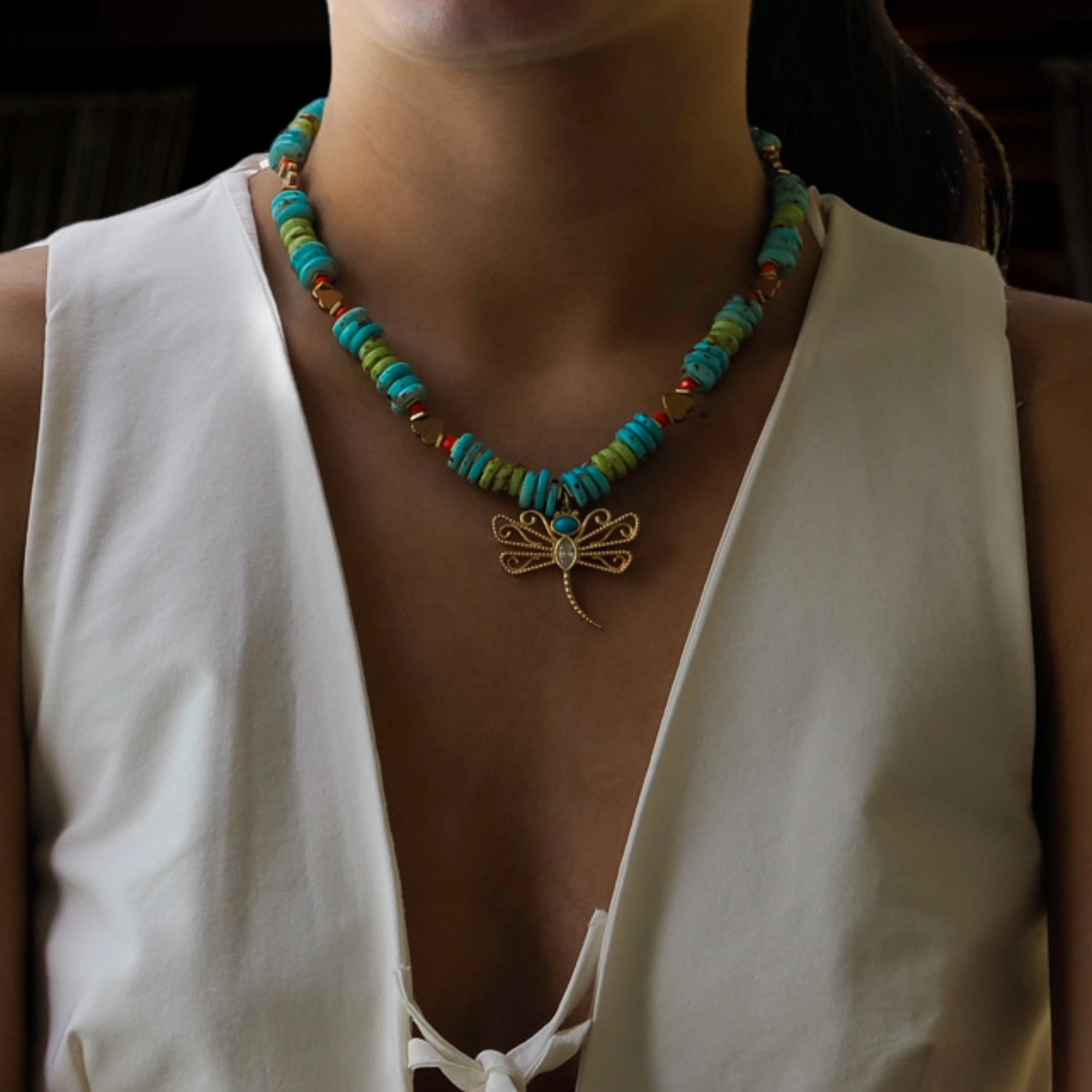 Handcrafted necklace with green African beads, gold hematite heart accents, and a dragonfly pendant.