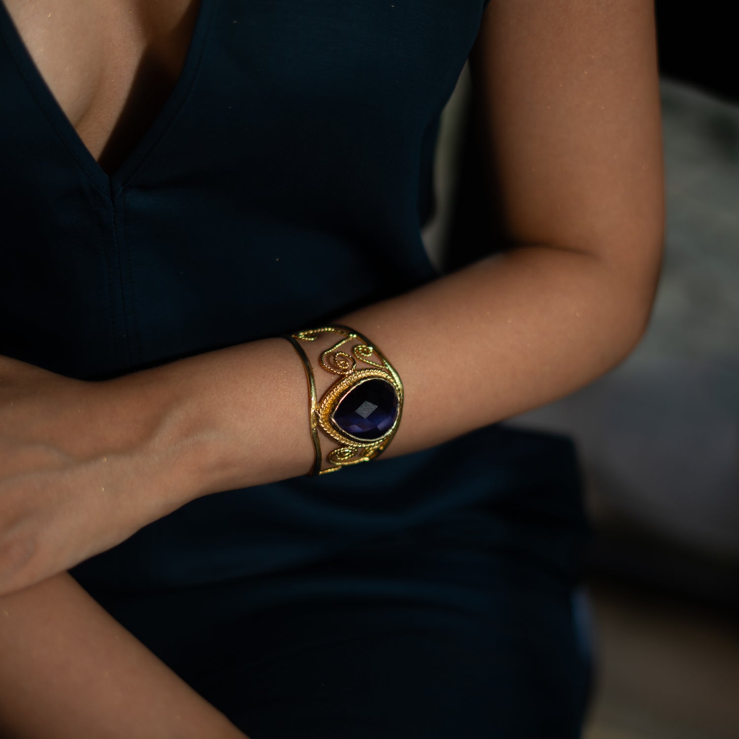 Chunky cuff bracelet in 24k gold-plated bronze, navy blue cat eye stone, ornate gold swirl pattern, vintage-inspired statement jewelry