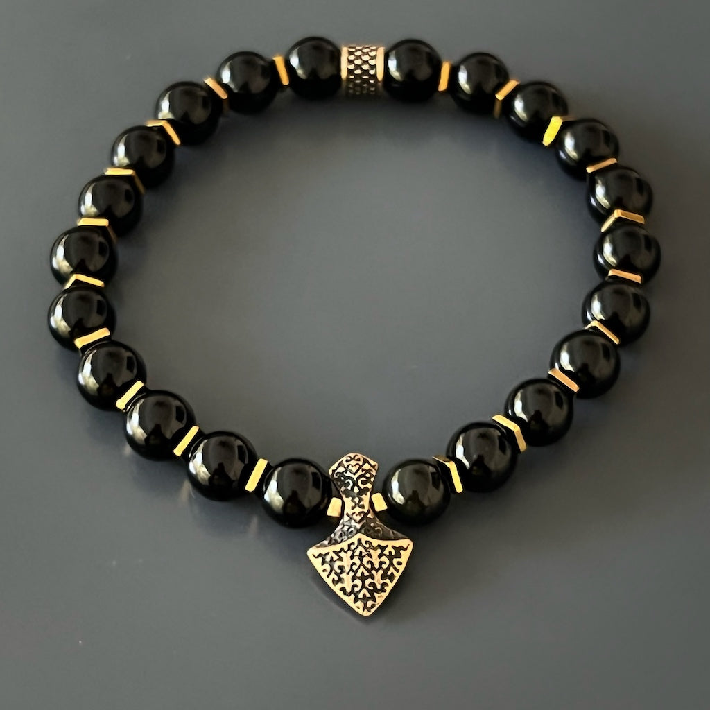 Close-up of black onyx bracelet with bronze gold-plated arrowhead symbolizing courage.