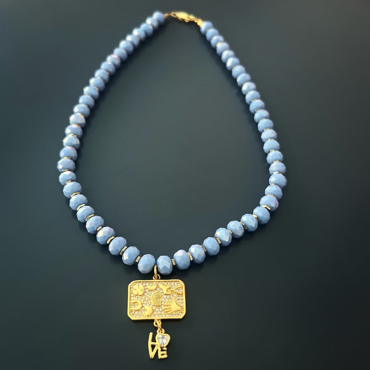 An elegant 18K gold plated love charm adds a touch of positivity and love.