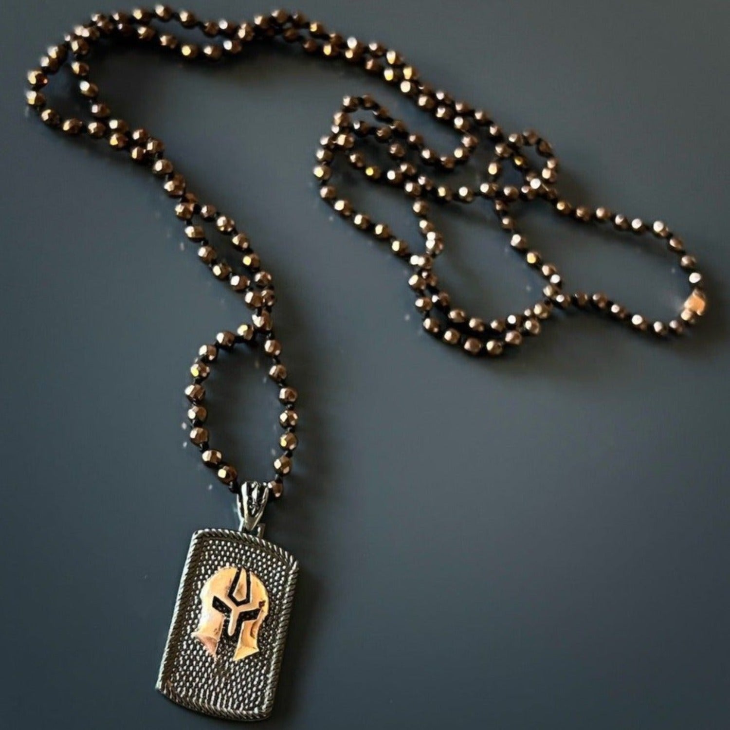 Close-up of detailed gladiator pendant on brown hematite stone bead necklace, 35" long.