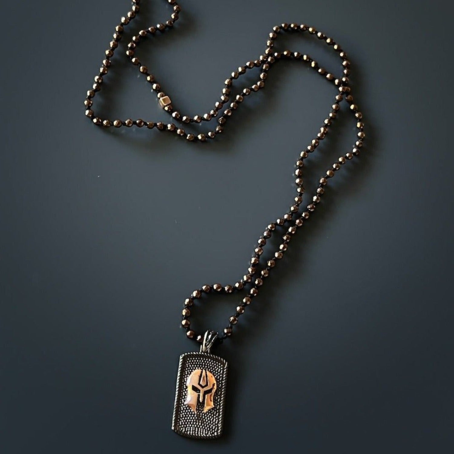 Bold men's jewelry with gladiator pendant in rose gold over silver and earthy hematite strand.