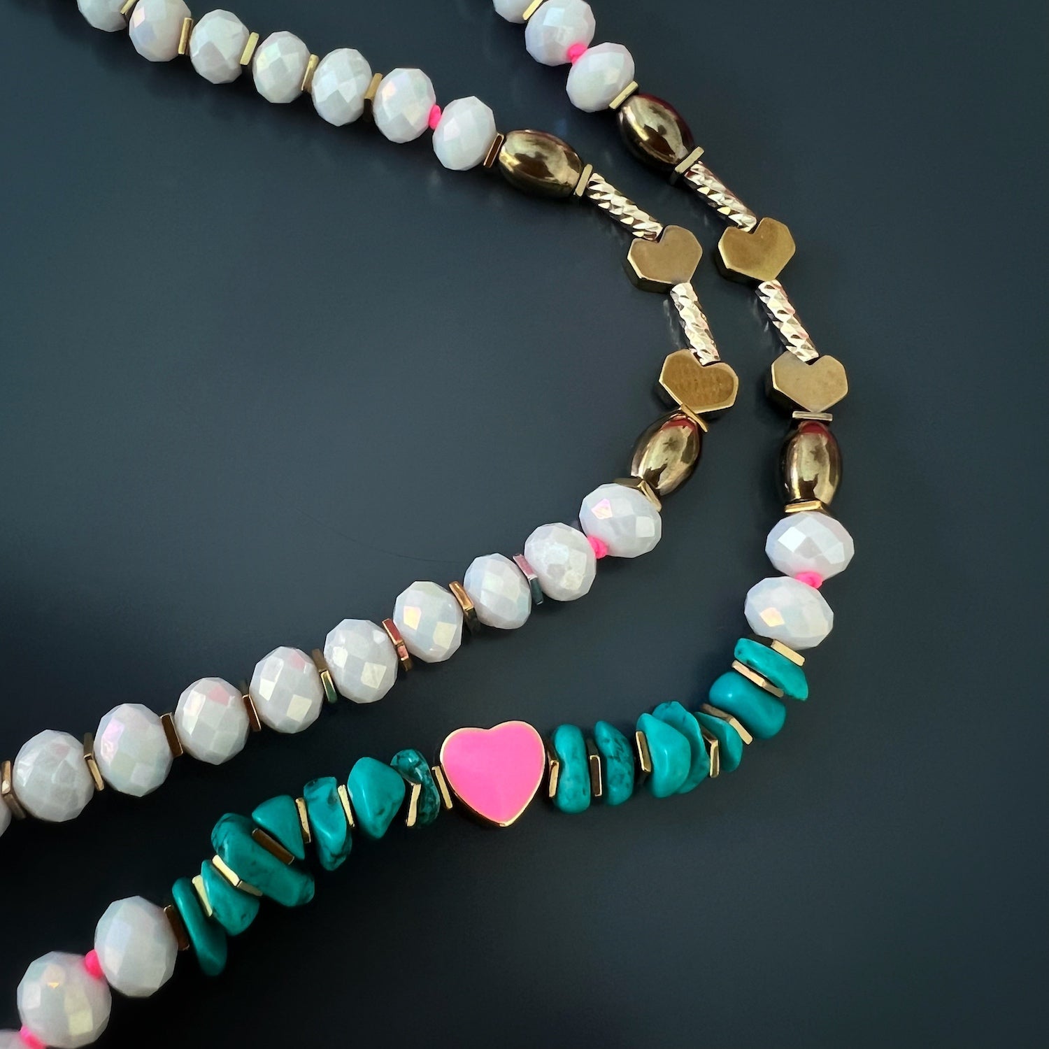 The necklace features turquoise nugget beads, white crystal beads, gold hematite spacers, and a beautiful 18K gold plated pink enamel heart pendant and love charm.
