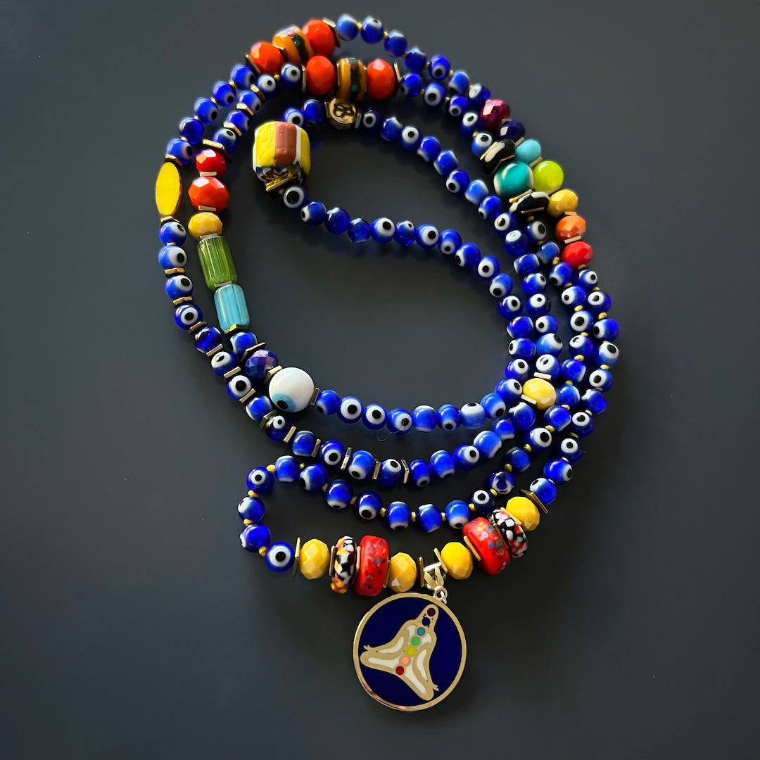 A depiction of the Nepal meditation beads and the hand-knotted jewelry rope in the Evil Eye Chakra Mala Necklace. These elements emphasize the necklace's connection to mindfulness and spiritual practices.