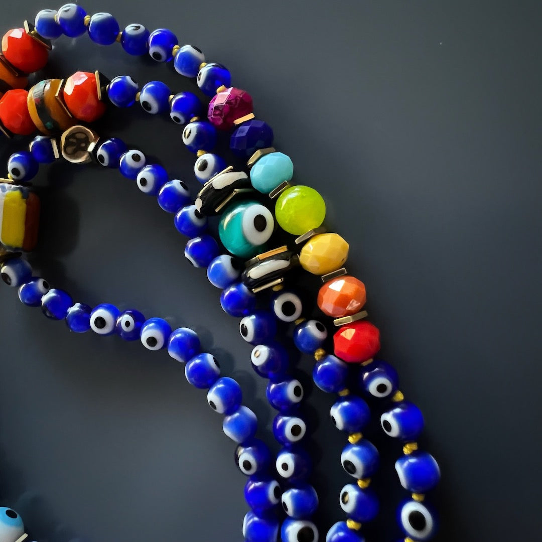 A showcase of the evil eye beads and hematite stone spacers in the Evil Eye Chakra Mala Necklace. These beads provide protection against ill intent and reflect negative energies back to their source.