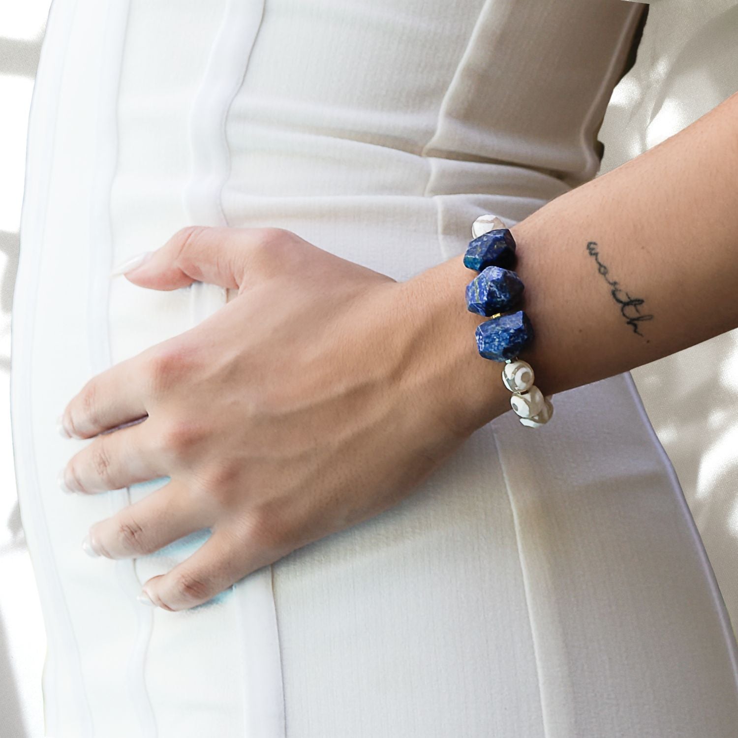 Hand model wearing Eye of Love Lapis Lazuli Bracelet - Handcrafted with Lapis Lazuli, White Nepal agate, and a Gold plated blue enamel heart bead.