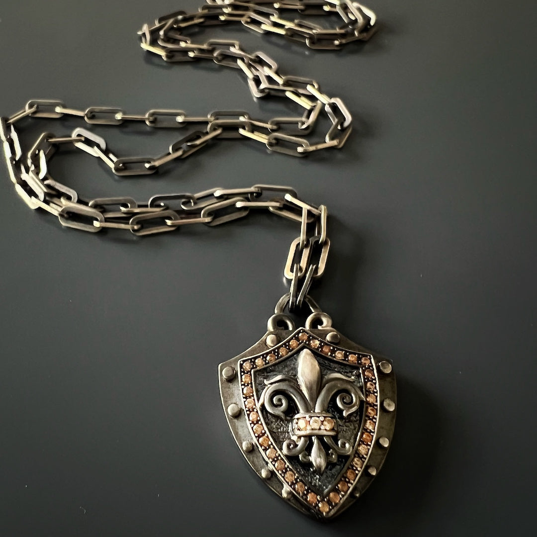 Bold Fleur de Lis Shield Jewelry - Handcrafted necklace showcasing a striking Fleur de Lis shield pendant made of engraved 925 silver with brown zircon stones.