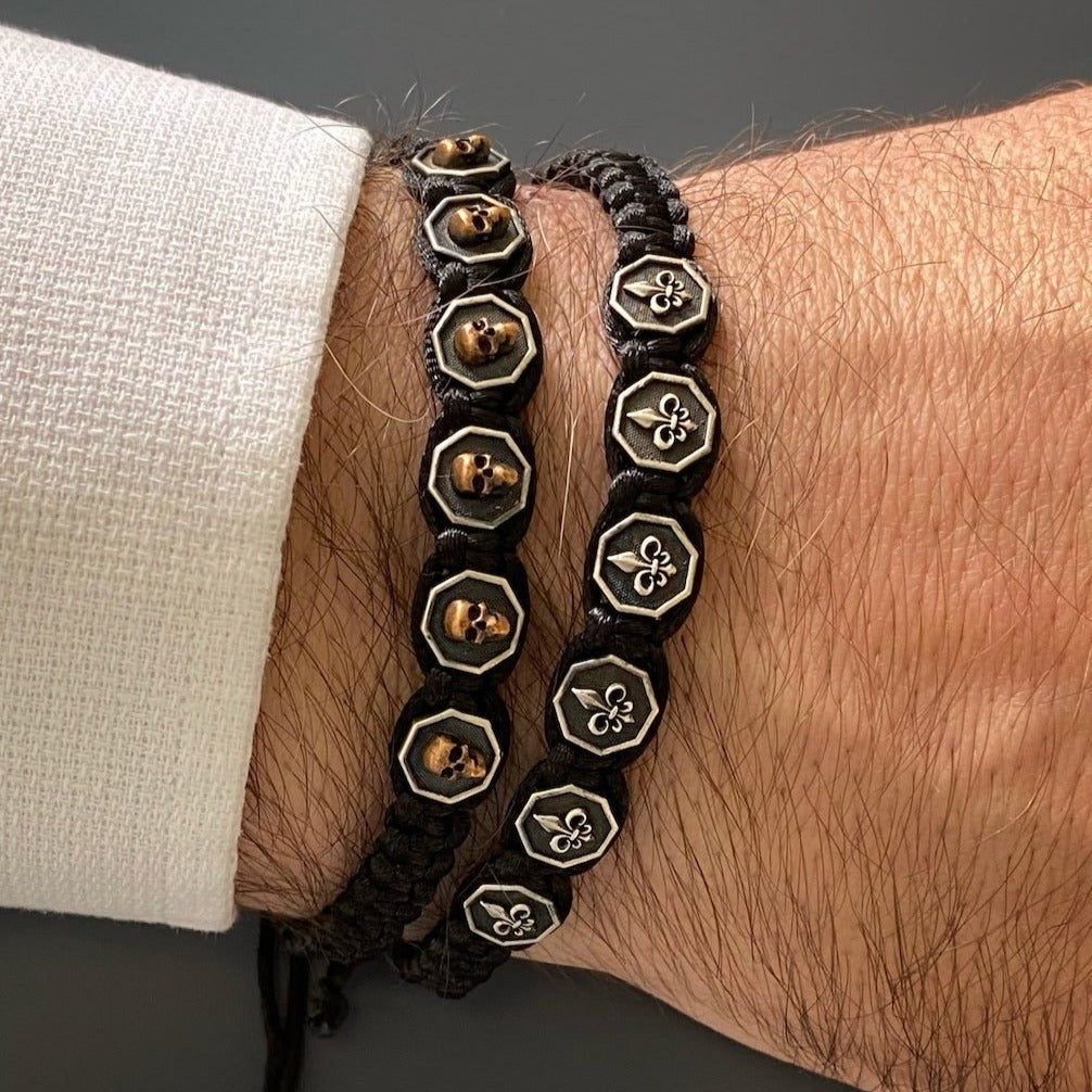 Stylish hand model wearing Fleur De Lis Men's Bracelet - Handmade bracelet featuring a woven design, adjustable size, and silver Fleur De Lis charms, perfect for fashionable men
