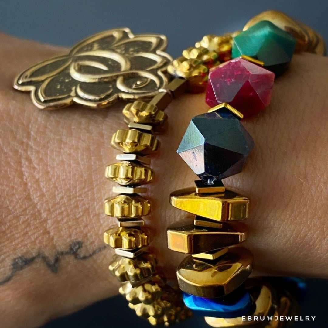 Spiritual hand model wearing Flower Of Life Bracelet - Unique jewelry piece with Om Mani Padme Hum mantra bead, Lotus Flower charm, and gold color hematite beads, symbolizing enlightenment and inner peace