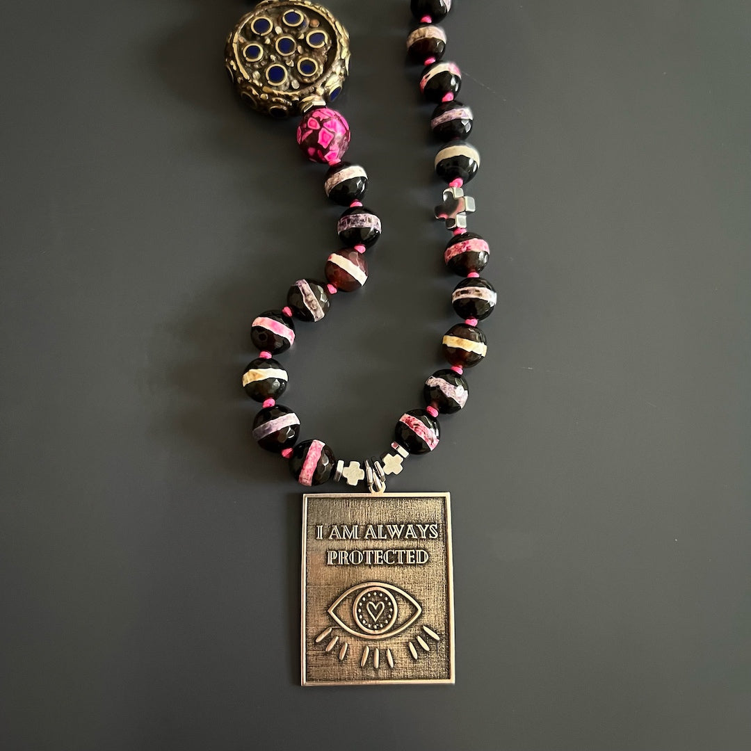 This image captures the beauty and significance of the I Am Always Protected Necklace, featuring silver hematite stone spacers and a sterling silver Evil Eye pendant.
