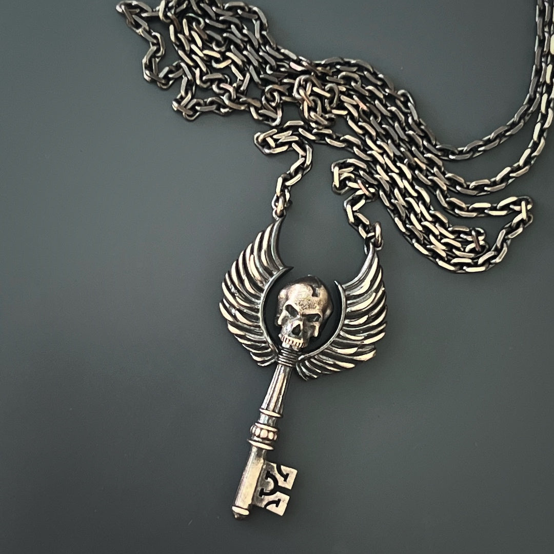 The Key Skull Silver Necklace elegantly drapes around the neck, adding a touch of edginess and sophistication to the overall look.
