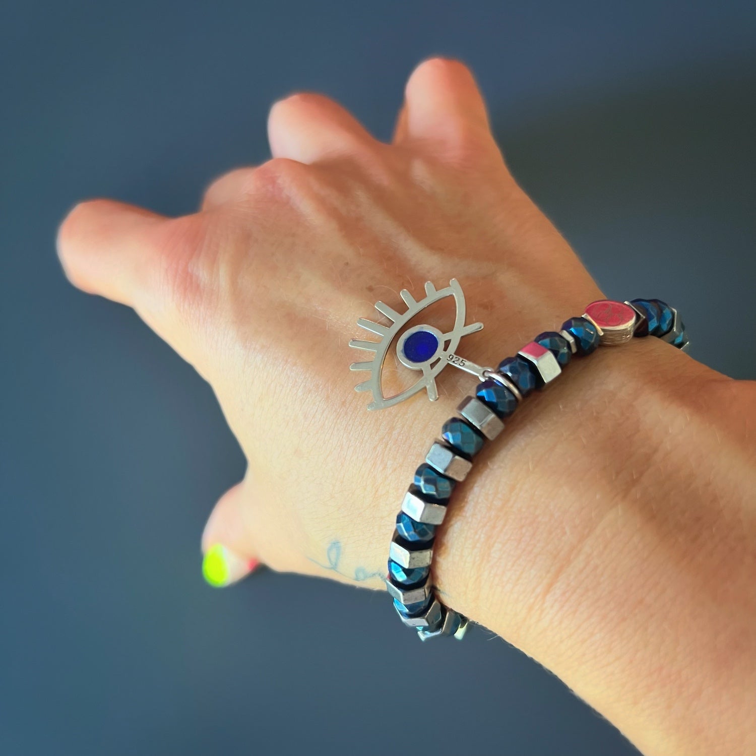 With the Nazar Bracelet adorning the hand model's wrist, the sterling silver evil eye charm catches the light, creating a captivating shine.
