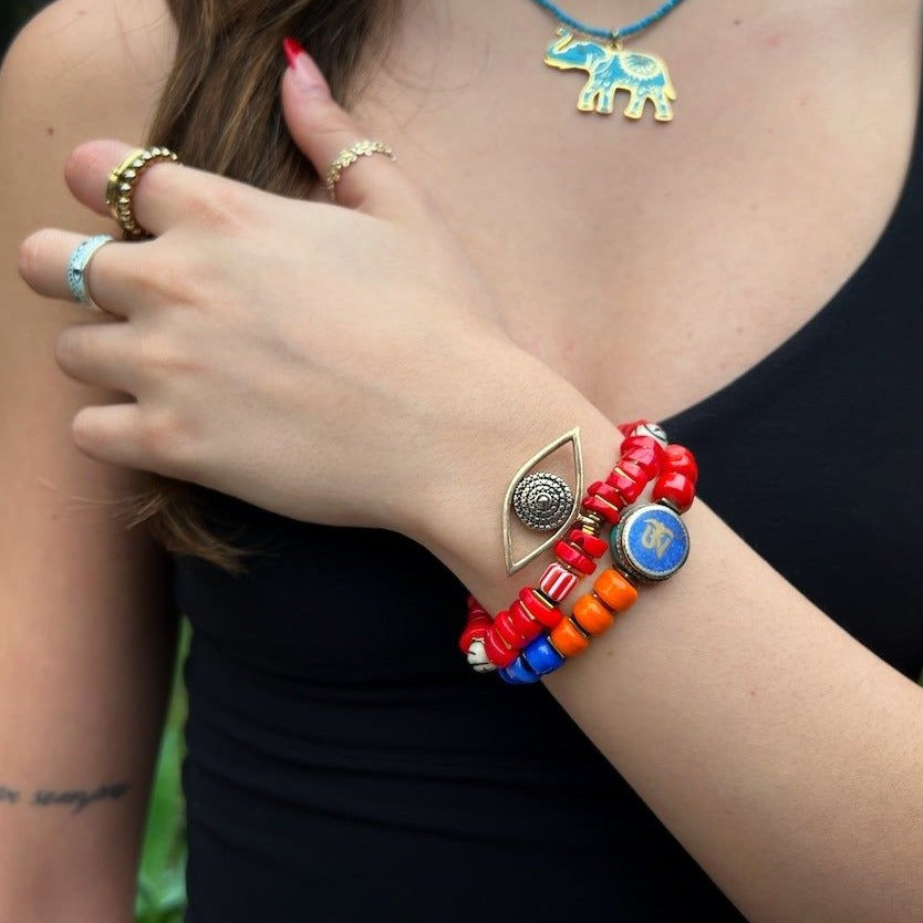 Experience the spiritual and protective energy of the Red Coral Evil Eye Bracelet as it graces the hand model&#39;s wrist, adorned with red coral beads and a prominent evil eye charm.