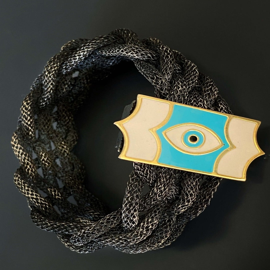 Immerse yourself in the beauty of the Silver Braided Evil Eye Bracelet, a handmade accessory that exudes charm and symbolism.