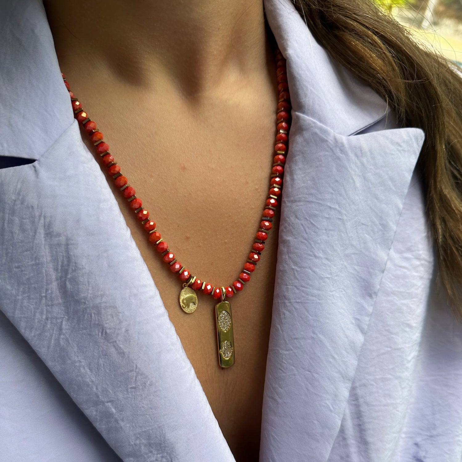 Model wearing the stunning Summer Journey Necklace with orange crystal beads and an elegant Hamsa pendant
