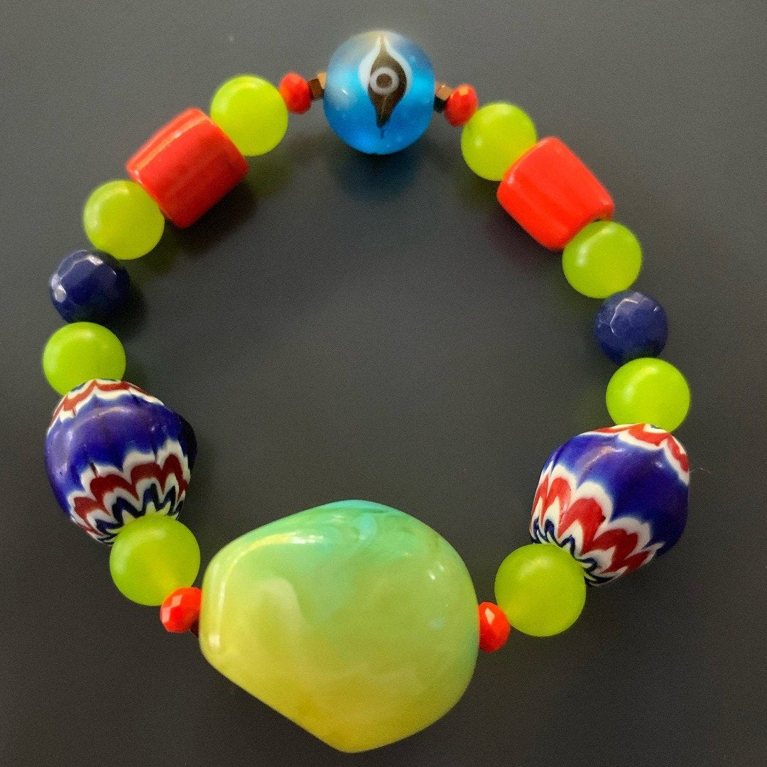 Handcrafted with care, the Color of Life Bracelet combines African beads, green and blue jade stone beads, Nepal beads, and an evil eye bead to create a stylish and meaningful accessory. 